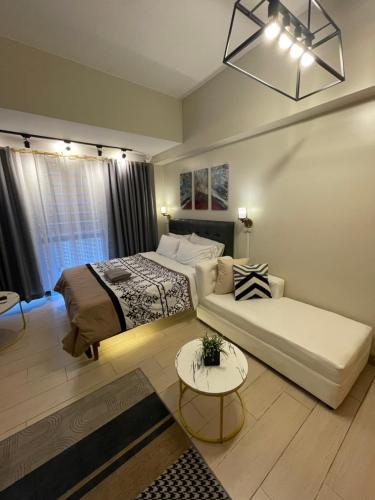 ein Schlafzimmer mit einem Bett, einem Sofa und einem Tisch in der Unterkunft Gorgeous One Eastwood Ave Suite in Manila