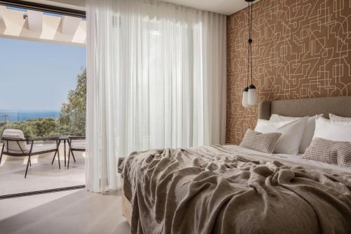 1 Schlafzimmer mit einem Bett und einem Balkon mit einem Tisch in der Unterkunft Gioarde Luxury Villa in Akrotiri