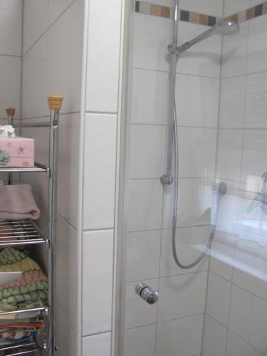 La salle de bains est pourvue d'une douche et de carrelage blanc. dans l'établissement #1Gemütliches ruhiges sonniges Balkonzimmer mit Gemeinschaftsbad W-Lan Airport nah Late Night Check in, à Trunkelsberg