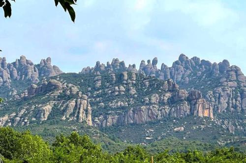 a large rocky mountain with trees in front of it at Secrets of Montserrat in El Bruc