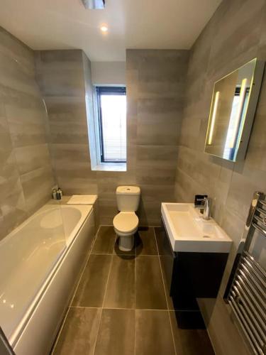 a bathroom with a tub and a toilet and a sink at Modern City Centre Flat in Norwich