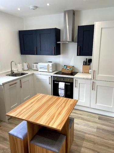 a kitchen with white cabinets and a wooden table at Modern City Centre Flat in Norwich