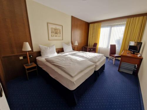 ein Hotelzimmer mit einem großen Bett und einem TV in der Unterkunft Hotel Regina in Sankt Augustin