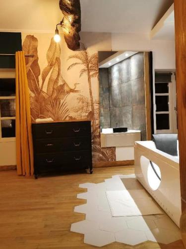 a bathroom with a black dresser and a painting on the wall at Suite Penthouse Romantique avec Jacuzzi, Confolens, Charente in Confolens