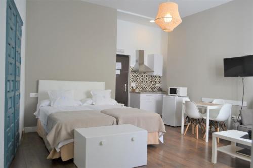 a white bedroom with two beds and a kitchen at SunShine Barroso Centro in Córdoba