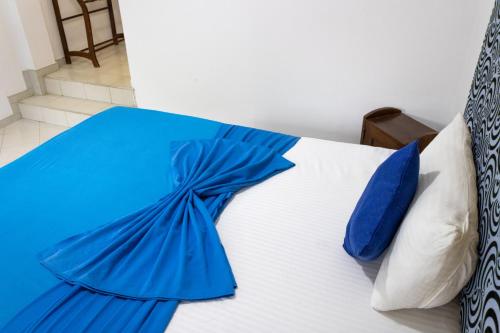 a bed with blue sheets and blue pillows on it at National Holiday Resort in Mahiyangana