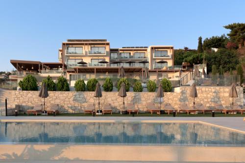 eine Gruppe von Sonnenschirmen und Stühlen neben einem Gebäude in der Unterkunft Irida Hotel Agia Pelagia in Agia Pelagia