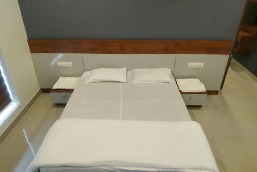 ein Schlafzimmer mit zwei weißen Betten in einem Zimmer in der Unterkunft Himani Heritage Resorts, formerly Camp Nishani Holidays in Madikeri