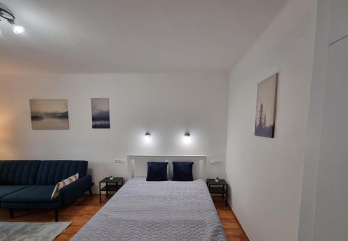 um quarto com 2 camas e um sofá azul em Barcika Apartman em Kazincbarcika
