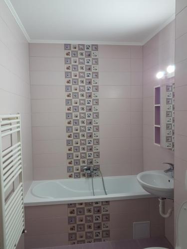 a bathroom with a bath tub and a sink at Green apartament in Şelimbăr