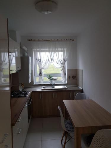 a kitchen with a table and a window with curtains at Green apartament in Şelimbăr