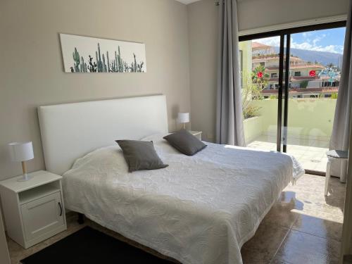 a bedroom with a white bed and a large window at Bahia I in Puerto de la Cruz