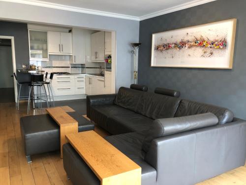 a living room with a black couch and a kitchen at Modern apartment at 2 steps from beach in Ostend