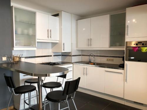 a kitchen with white cabinets and a table and chairs at Modern apartment at 2 steps from beach in Ostend