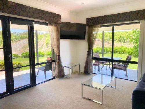 a living room with a glass table and sliding glass doors at Shiraz Cottage - A Vineyard Retreat in Barossa Valley in Rowland Flat
