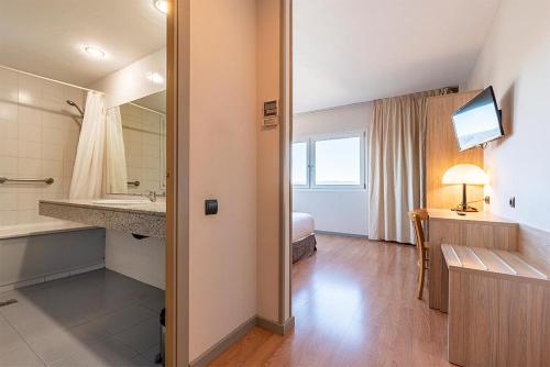 een hotelkamer met een badkamer met een wastafel en een bed bij Hotel Air Penedès in Vilafranca del Penedès