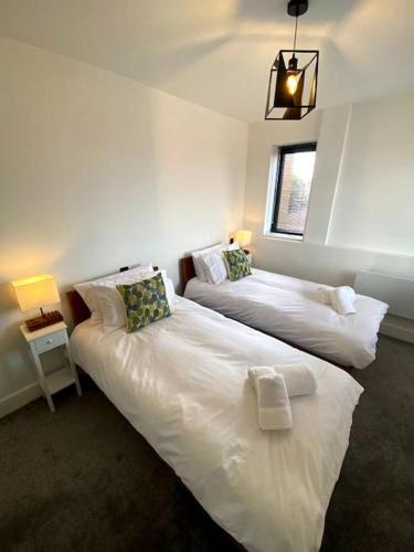 two beds in a room with two lamps and a window at Stylish City Centre Flat in Norwich
