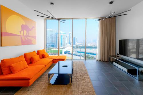 a living room with an orange couch and a tv at Emirates Sports Hotel Apartments, Dubai Sports City in Dubai