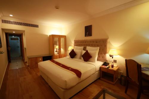 a hotel room with a large bed and a desk at Saj Luciya -A Classified 4 Star Hotel in Trivandrum