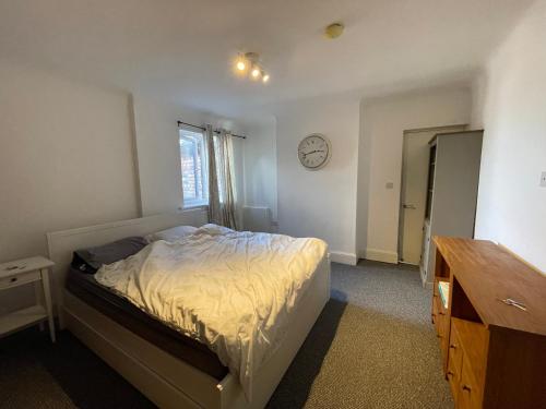 - une chambre avec un lit et une horloge murale dans l'établissement Lovely 2 bedrooms apartment West derby Liverpool, à Deysbrook