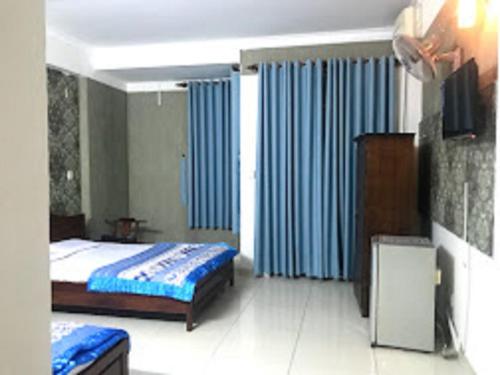 1 dormitorio con 1 cama y cortinas azules en Bluesky Tan Son Nhat Golf Center Hotel, en Ho Chi Minh