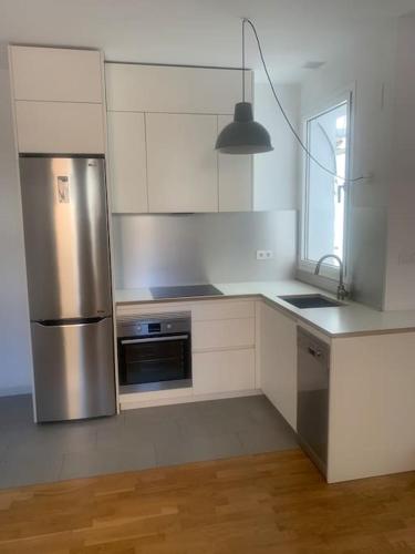 una cucina con frigorifero in acciaio inossidabile e finestra di Fernando Garrido, estudio ideal en Chamberí a Madrid