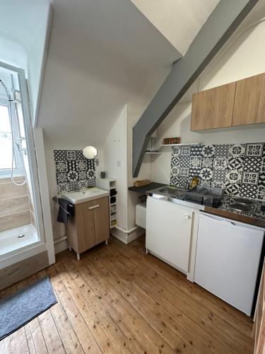 a large kitchen with white cabinets and a staircase at Le Ty Kerguelen in Quimper