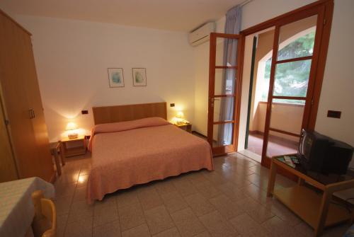 a bedroom with a bed and a window and a tv at Residence Il Gabbiano Azzurro in Marciana Marina