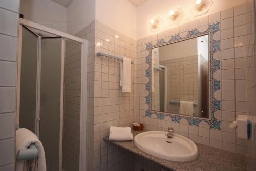 ein Bad mit einem Waschbecken und einem Spiegel in der Unterkunft Residence Il Gabbiano Azzurro in Marciana Marina