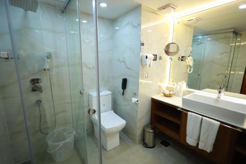a bathroom with a shower and a toilet and a sink at Saj Luciya -A Classified 4 Star Hotel in Trivandrum