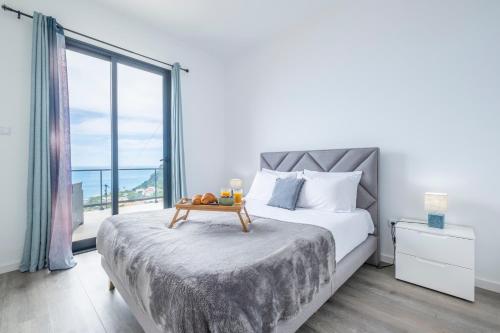 a bedroom with a bed and a large window at Shell House by GALMI in Arco da Calheta