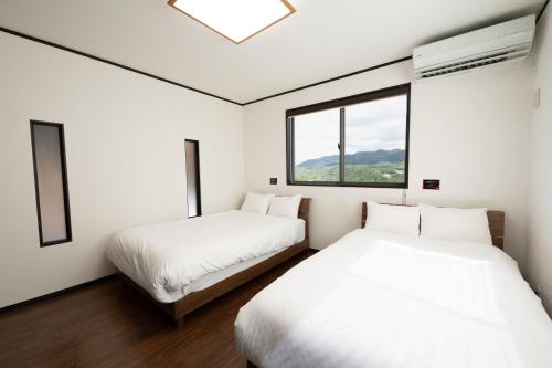 2 Betten in einem Zimmer mit Fenster in der Unterkunft トワイライトヒルズ Twilight Hills in Motobu