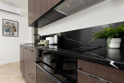 a kitchen with a black counter top and wooden cabinets at Elegant Mokotow Apartment with Parking & AC near Royal Baths Warsaw by Renters Prestige in Warsaw