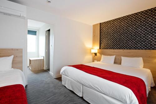 ヴァンヌにあるキリアド ヴァンヌ ソントレ ヴィーレのホテルルーム ベッド2台(赤いシーツ付)