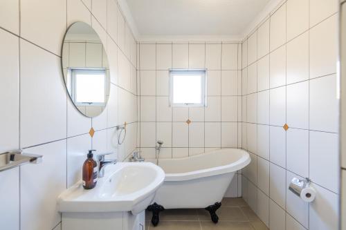a white bathroom with a tub and a sink at @41 in Windhoek