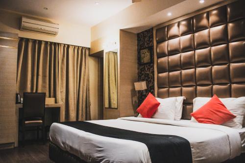 um quarto de hotel com uma cama grande com almofadas vermelhas em Hotel Radiant em Calcutá