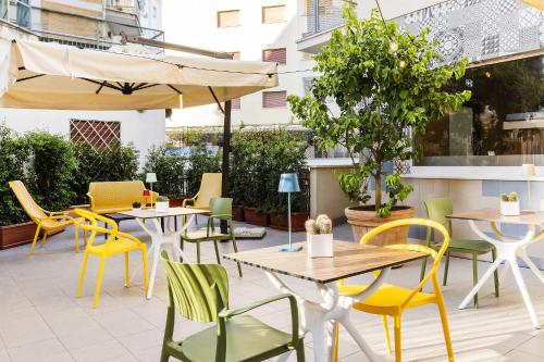 a patio with tables and chairs and an umbrella at Adesso Hotel in Rome