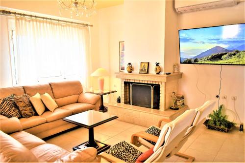 a living room with a couch and a tv at Ioanna's Villa 10 minutes walking from sea in Gra Liyiá