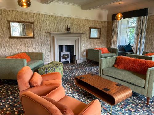 ein Wohnzimmer mit Sofas und Stühlen sowie einem Kamin in der Unterkunft Moresby Hall Country House Hotel in Whitehaven