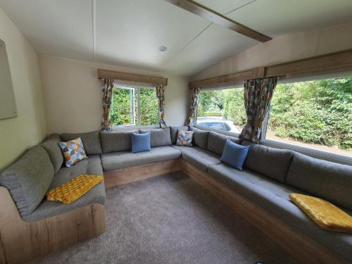 a living room with a large couch and windows at 24 Chestnut Grove Caravan in Humberston