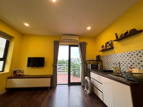 eine Küche mit gelben Wänden und einer Glasschiebetür in der Unterkunft Bhome Văn Miếu in Hanoi