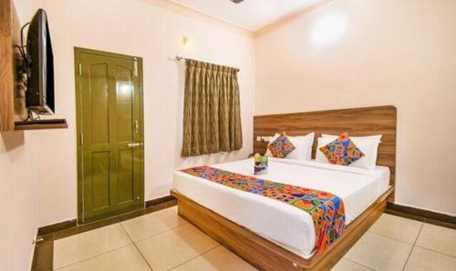 een slaapkamer met een groot bed en een groene deur bij FabHotel Radha Residency in Pondicherry