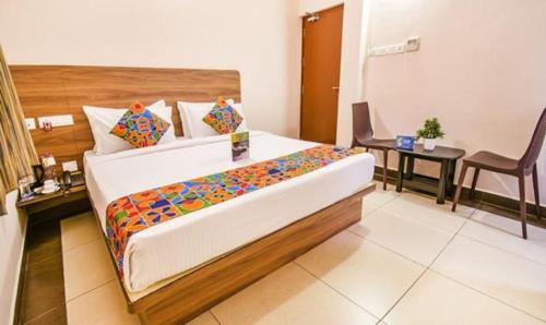 een slaapkamer met een bed, een tafel en een stoel bij FabHotel Radha Residency in Pondicherry