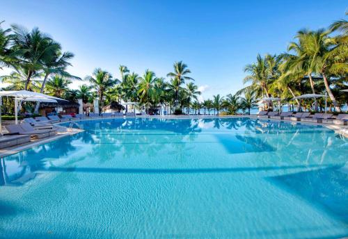 a large swimming pool with chairs and palm trees at Viva Dominicus Beach by Wyndham, A Trademark All Inclusive in Bayahibe