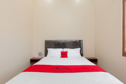 1 dormitorio con 1 cama con arco rojo en RedDoorz Syariah near Lemahabang Station, en Glonggong