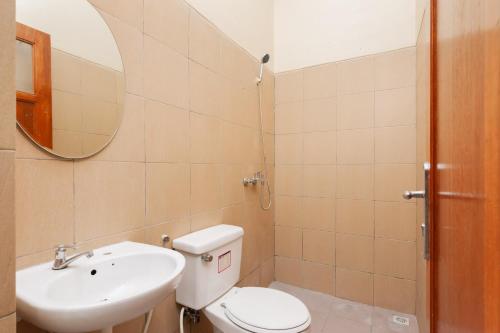 a bathroom with a toilet and a sink and a mirror at RedDoorz Syariah near Lemahabang Station in Glonggong