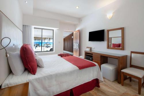 a bedroom with a bed and a desk and a television at Viva Dominicus Beach by Wyndham, A Trademark All Inclusive in Bayahibe