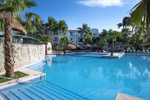 a large swimming pool with palm trees in a resort at Viva Azteca by Wyndham, A Trademark All Inclusive Resort in Playa del Carmen