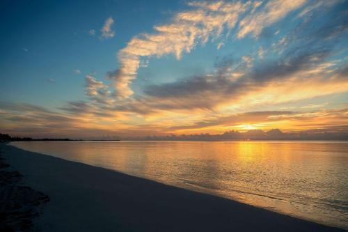 a sunset on a beach with the water and clouds at Viva Fortuna Beach by Wyndham, A Trademark All Inclusive in Freeport