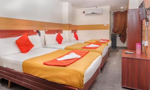 Duas camas num quarto com toalhas vermelhas e brancas em HOTEL BOOPATHI Madurai em Madurai
